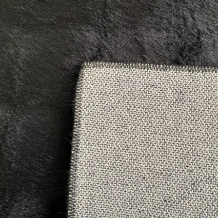 Detail koberca v čiernej farbe s bublinkovým vzorom, ukazujúci textúru a okraj koberca.